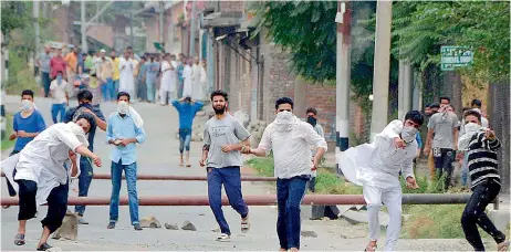  ??  ?? Kashmiri protesters throw stones as they clash with policemen in Srinagar.