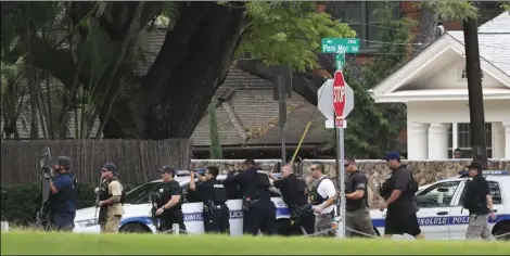  ?? JAMM AQUINO/HONOLULU STAR-ADVERTISER VIA AP ?? Honolulu police take up defensive positions with their weapons after a shooting and domestic incident at a residence on Hibiscus Road near Diamond Head on Sunday, in Honolulu. Witnesses say at least two Honolulu police o cers were shot and two civilians were injured.