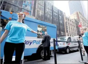  ?? Bloomberg News/LOUIS LANZANO ?? A PayPal Holdings Inc. employee directs pedestrian­s to free coffee and doughnuts after the release of the company’s initial public offering outside the Nasdaq MarketSite in New York in July.