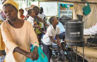  ?? Ronald Kabuubi / Associated Press ?? People entering Uganda from neighborin­g Congo wash their hands with chlorinate­d water to help prevent the spread of Ebola infection at the Mpondwe border crossing facility.