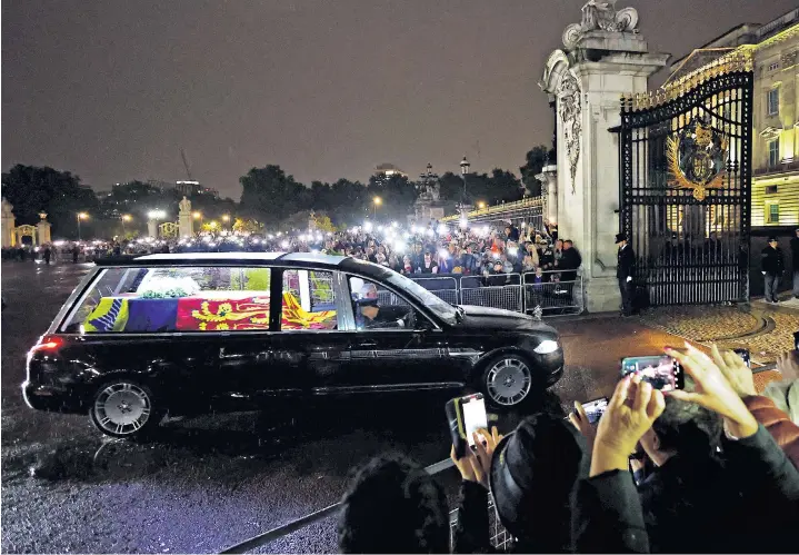  ?? ?? Crowds watch the hearse carrying the coffin of Queen Elizabeth II arrive at Buckingham Palace after it flew into RAF Northolt from Scotland