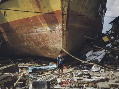  ?? Picture: Getty. ?? A boy stands by a stranded ship after the tsunami struck Donggala, central Sulawesi.