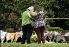  ?? MATT ROURKE — THE ASSOCIATED PRESS ?? Two people support each other in front of flowers at a makeshift memorial at the Tree of Life Synagogue in Pittsburgh, Sunday. Robert Bowers, the suspect in Saturday’s mass shooting at the synagogue, expressed hatred of Jews during the rampage and told officers afterward that Jews were committing genocide and he wanted them all to die, according to charging documents made public Sunday.