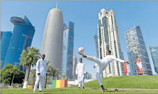  ?? ?? Varios jóvenes qataríes juegan con un balón en el Corniche, con el skyline del West Bay de Doha por detrás de ellos.