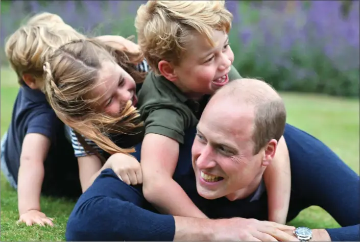 ??  ?? PORTRAIT OF A HAPPY FAMILY: Fizzing with laughter, George, Charlotte and little Louis clamber over Prince William in this exuberant image, celebratin­g both Father’s Day and the Duke’s 38th birthday