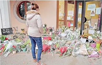  ?? — APP photo ?? A woman looks at flowers at the entrance of a middle school in Conflans-Sainte-Honorine after a teacher was decapitate­d by an attacker who was later shot dead by policemen.