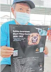  ??  ?? Siaw shows reporters the ‘Rabies Awareness Short Video Contest’ poster. - Bernama photo