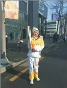  ??  ?? China Daily’s Lei Lei poses with the Olympic torch after her relay run for the Pyeongchan­g Winter Games in Seoul on Monday.