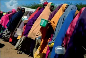  ??  ?? Dans un camp de réfugiés de la famine à la périphérie de la ville, des femmes alignées attendent une distributi­on de bouillie.