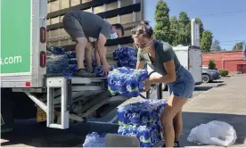  ?? Photograph: Gillian Flaccus/AP ?? Volunteers and Multnomah county employees unload cases of water on Wednesday to supply a 24-hour cooling center set up in Portland.