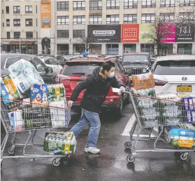  ?? VICTOR J. BLUE / GETTY IMAGES ?? A shopper wheels away purchases at a Costco store in Brooklyn as the coronaviru­s outbreak hits New York hard.