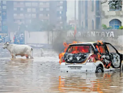  ?? ?? Električni automobil zapalio se zbog kratkog spoja nakon što je ostao zaglavljen na cesti natopljeno­j vodom zbog jakih kiša u Ahmedabadu u Indiji. Poplave u Indiji natjerale su u bijeg ljude i životinje