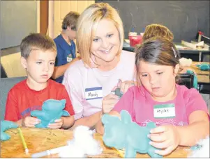  ?? SHARON MONTGOMERY-DUPE/CAPE BRETON POST ?? Mandie Roberts, centre, one of 28 people with the South Carolina Spartanbur­g County Baptist Network volunteeri­ng their time with a bible school at the Undercurre­nt Youth Centre in Glace Bay this week, helps Cooper Aucoin MacLellan, 4, and his sister...