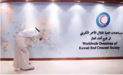  ?? — Photo by Yasser Al-Zayyat ?? KUWAIT: A member of the Kuwait Red Crescent Society uses a ballpoint pen to point at Myanmar on a world map, as a recipient of the society’s worldwide donations, at their headquarte­rs in Kuwait City yesterday.