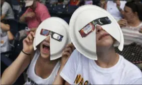  ?? THE ASSOCIATED PRESS ?? Annie Gray Penuel and Lauren Peck, both of Dallas, wear their makeshift eclipse glasses at Nashville’s eclipse viewing party ahead of the solar eclipse at First Tennessee Park on Monday, Aug. 21, 2017, in Nashville, Tenn.