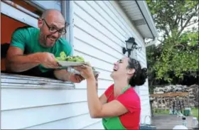  ?? DIGITAL FIRST MEDIA FILE PHOTO ?? David Ryle hands plates of fresh greens to his smiling wife Wendy during a harvest dinner held out in the field at their home. Eating healthy foods such as vegetables can lead to more positive feelings.