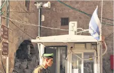  ?? ?? An Israeli soldier stands under a surveillan­ce camera at a checkpoint in the flashpoint Palestinia­n city of Hebron.