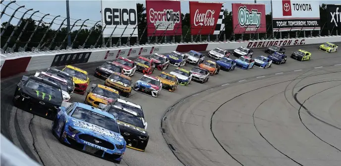  ?? GETTy IMAgES ?? BACK ON TRACK: Kevin Harvick, front, leads the pack en route to the win during the NASCAR Cup Series The Real Heroes 400 at Darlington Raceway on Sunday in Darlington, S.C. At top, Firecracke­r 400 winner Richard Petty showers the crowd with champagne at Daytona Internatio­nal Speedway on July 4, 1984, the last time a race was held on a Wednesday.