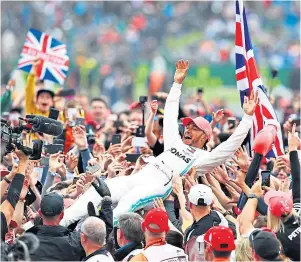  ??  ?? POPULAR: Lewis Hamilton celebrates with fans after winning at Silverston­e in July