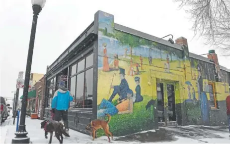  ?? Helen H. Richardson, Denver Post file ?? Crawford Frazer walks his dogs Owen, left, and Chester along the main district in downtown Edgewater and past a mural on the side of the Providence Tavern. More businesses are using murals to attract customers with Instragram accounts with an eye for...