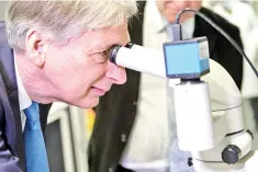  ??  ?? Britain’s Chancellor of the Exchequer Philip Hammond uses a microscope to examine protein crystals during his visit to The Francis Crick Institute in London on October 25. Britain’s economy gently picked up speed in the third quarter, official data...
