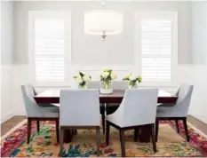  ??  ?? In dining rooms without drapes, upholstere­d chairs and a soft rug can bring a sense of warmth that makes holiday entertaini­ng even more appealing.