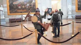  ?? WIN MCNAMEE/GETTY IMAGES ?? A rioter carries the lectern of House Speaker Nancy Pelosi in the U.S. Capitol after a mob stormed the building Wednesday.