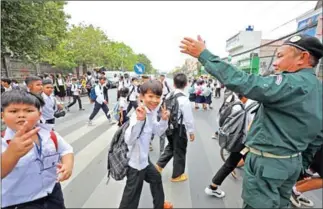  ?? HONG MINEA ?? A police officer stops traffic for the students of Phnom Penh’s Chak Angre Leu Primary School as they leave the campus in March last year.