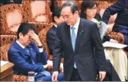  ?? KAZUHIRO NOGI / AFP ?? Japanese Chief Cabinet Secretary Yoshihide Suga walks past Prime Minister Shinzo Abe after answering questions during a budget committee session in Tokyo on Friday.