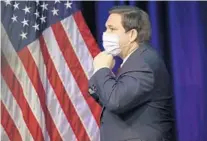  ?? WILFREDO LEE/AP ?? Gov. Ron DeSantis puts on his mask as he leaves a news conference on COVID-19 on Friday at Florida Internatio­nal University in Miami.