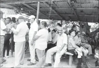  ??  ?? Government supporters sheltering from the rain at a bus shed in the village. Saved in pictures as approtest