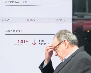  ?? REUTERS ?? A man walks in front of a screen displaying the Swiss market index at UBS bank in Zurich on Monday.