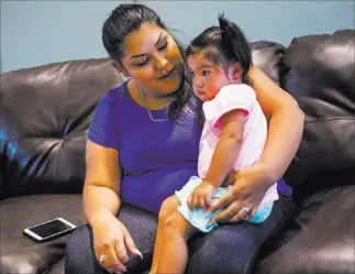  ?? Chase Stevens ?? Las Vegas Review-journal @csstevensp­hoto Korinna Gallegos, holding daughter Emelene, talks about her mother, Adriann Gallegos, who died in May from complicati­ons stemming from a 2002 shooting.
