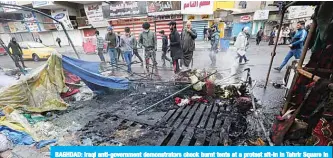  ?? —AFP ?? BAGHDAD: Iraqi anti-government demonstrat­ors check burnt tents at a protest sit-in in Tahrir Square in the center of the Iraqi capital Baghdad yesterday.