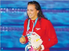  ?? DARKO BANDIC, THE ASSOCIATED PRESS ?? Canada’s gold-medal winner Kylie Masse shows off her medal after the 100-metre backstroke on Tuesday.