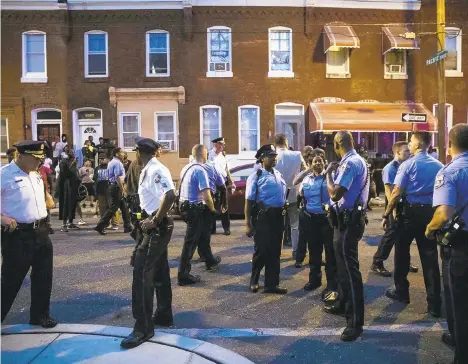  ?? PHOTOS BY MATT ROURKE/AP ?? Philadelph­ia officers gather for crowd control near a massive police presence set up outside a house as they investigat­e an active shooting situation on Wednesday.