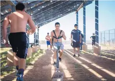  ??  ?? Jaguars’ quarterbac­k Cisco Leos trains by pulling a railroad tie backwards, part of an endurance relay.