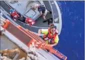  ?? Pictures: AP ?? RESCUED: Tasha Fuiava, an American who had been on the damaged sailboat, climbs the accommodat­ion ladder to board the amphibious dock landing ship USS Ashland.