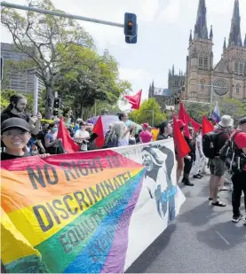  ?? Photos / AP ?? Protesters carry rainbow flags outside St Mary's Cathedral in Sydney.