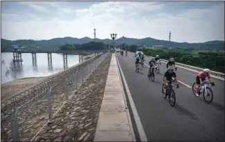  ?? ?? Members of the Qiyi bicycle club ride past the Miyun Reservoir on July 13 during the group ride.