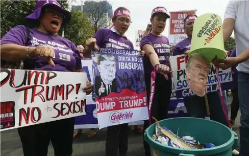  ??  ?? BEBERAPA aktivis membuang gambar Trump ke dalam tong sampah ketika tunjuk perasaan di hadapan kedutaan Amerika Syarikat di Manila, semalam. - AP