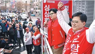  ?? Joint Press Corps ?? Han Dong-hoon, left, interim leader of the ruling People Power Party, holds his arms up with Ham Un-kyung, the party’s candidate running in Seoul’s Mapo-A constituen­cy, during a campaign event near Mangwon Station, Thursday, when official campaignin­g started for the April 10 general elections.