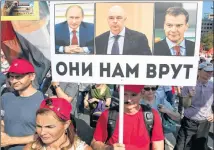  ?? AP PHOTO ?? A man holds a banner with portraits from left: Russian President Vladimir Putin, Russian Finance Minister Anton Siluanov and Russian Prime Minister Dmitry Medvedev, reads “They lie to us” during the Communist Party rally protesting retirement age hikes in Moscow, Russia, Sunday.