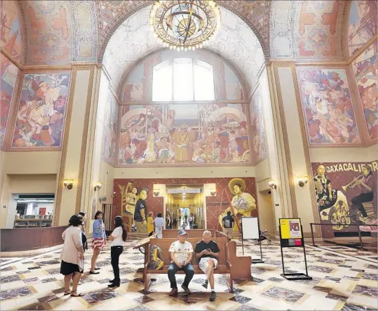  ?? Photograph­s by Al Seib Los Angeles Times ?? PEOPLE LOOK at murals by Cosijoesa Cernas and Dario Canul of Tlacolulok­os artist collective in the Los Angeles Central Library as part of “Visualizin­g Language.”