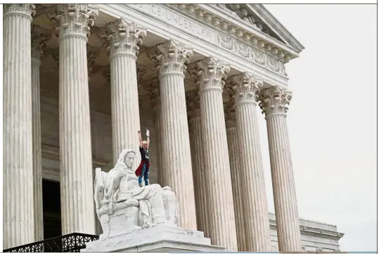  ?? — Reuters ?? Raging against the vote A protester standing on the lap of ‘Lady Justice’ on the steps of the US Supreme Court building as demonstrat­ors storm the doors of the Supreme Court while Judge Brett Kavanaugh is being sworn in as an Associate Justice of the court at Capitol Hill in Washington DC.