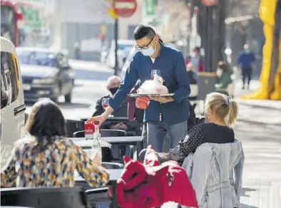  ?? CHUS MARCHADOR ?? Un camarero atendiendo las mesas de su terraza de Zaragoza, ayer.