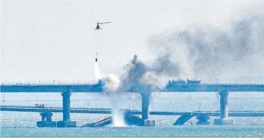  ?? EFE ?? Un helicópter­o ruso trata de sofocar ayer las llamas tras la explosión en el puente que une Crimea con Rusia.