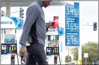  ?? (AP) ?? In this file photo, a person walks past a gas station around Victorvill­e, Calif.