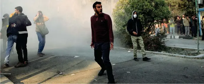  ??  ?? Fumo e rabbia Uno studente iraniano a Teheran durante le proteste anti governativ­e iniziate il 28 dicembre scorso. Secondo i primi bilanci degli scontri le vittime sono almeno 13, tra loro anche un agente (Foto Ap)