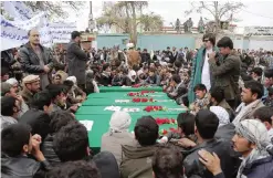  ??  ?? Afghan men gather around the coffins with the headless bodies of a group of Shiite Hazaras in Ghazni province yesterday. — AFP